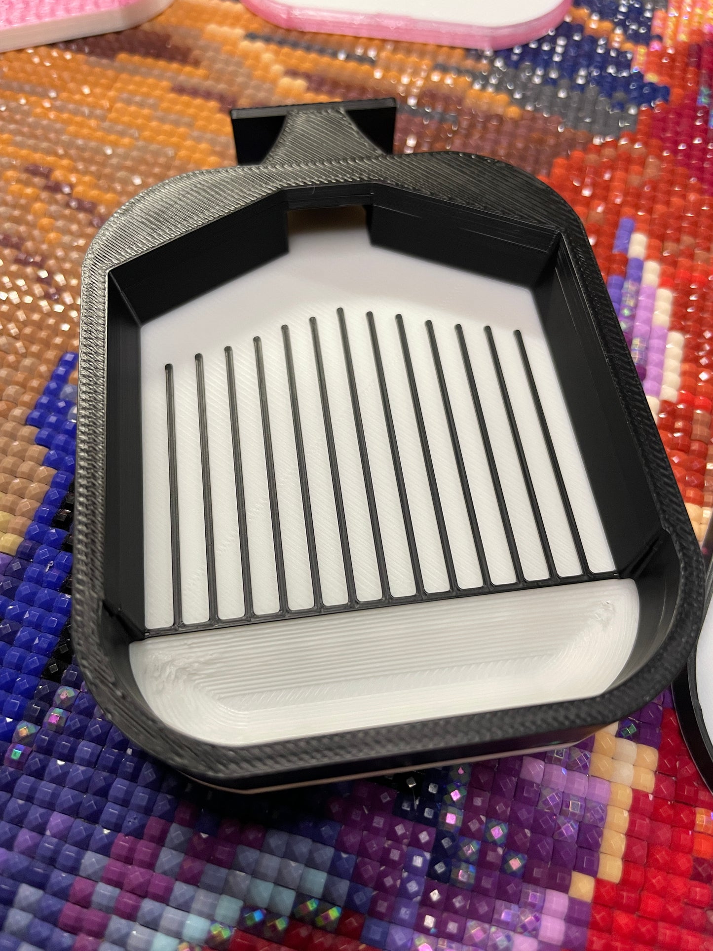 Black and white small diamond painting tray on colorful background, showcasing white base and grid design.