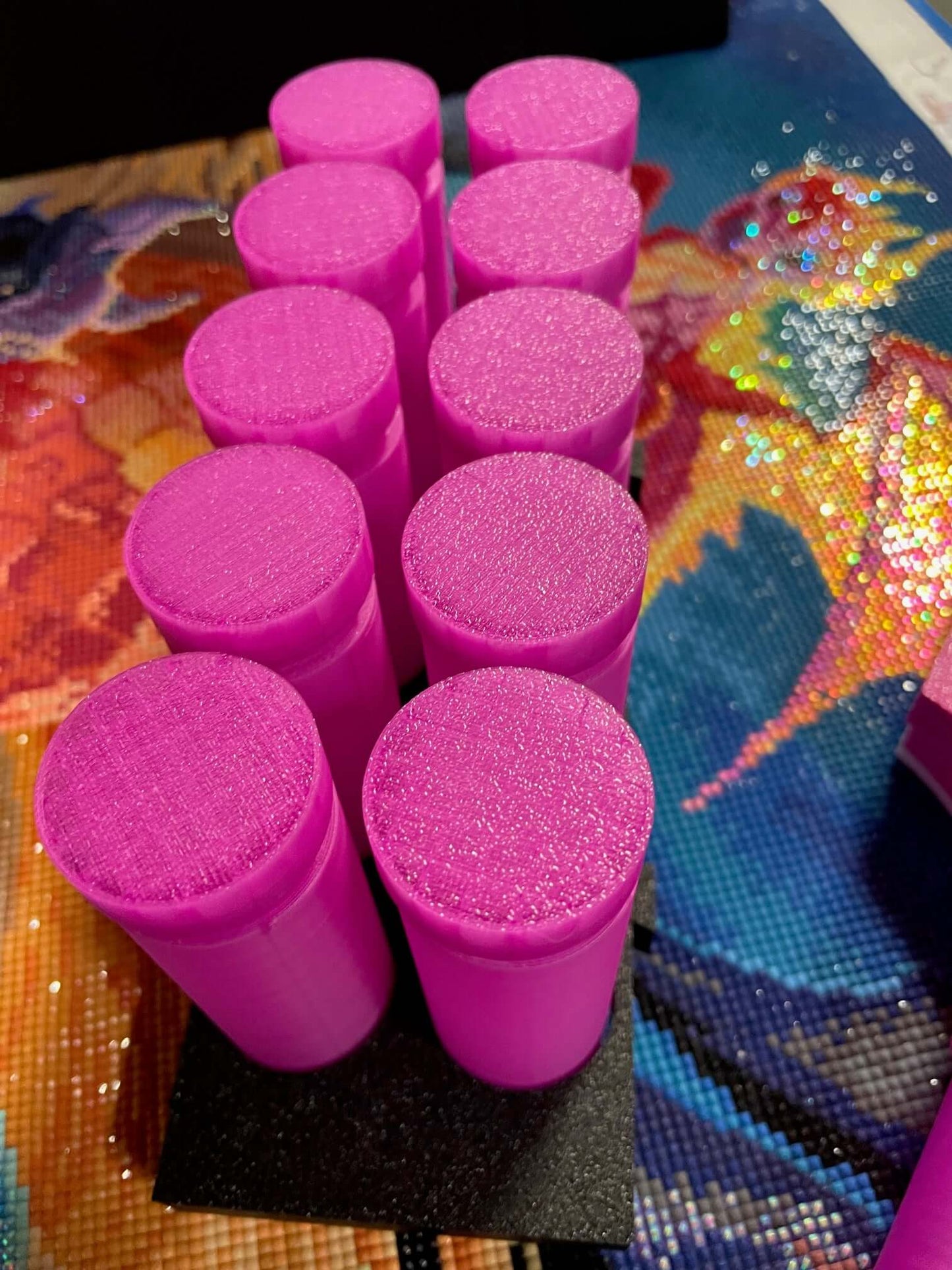 Pink Mist containers displayed upright on a black stand from the Screw & Shake Starter Kit against a colorful background.
