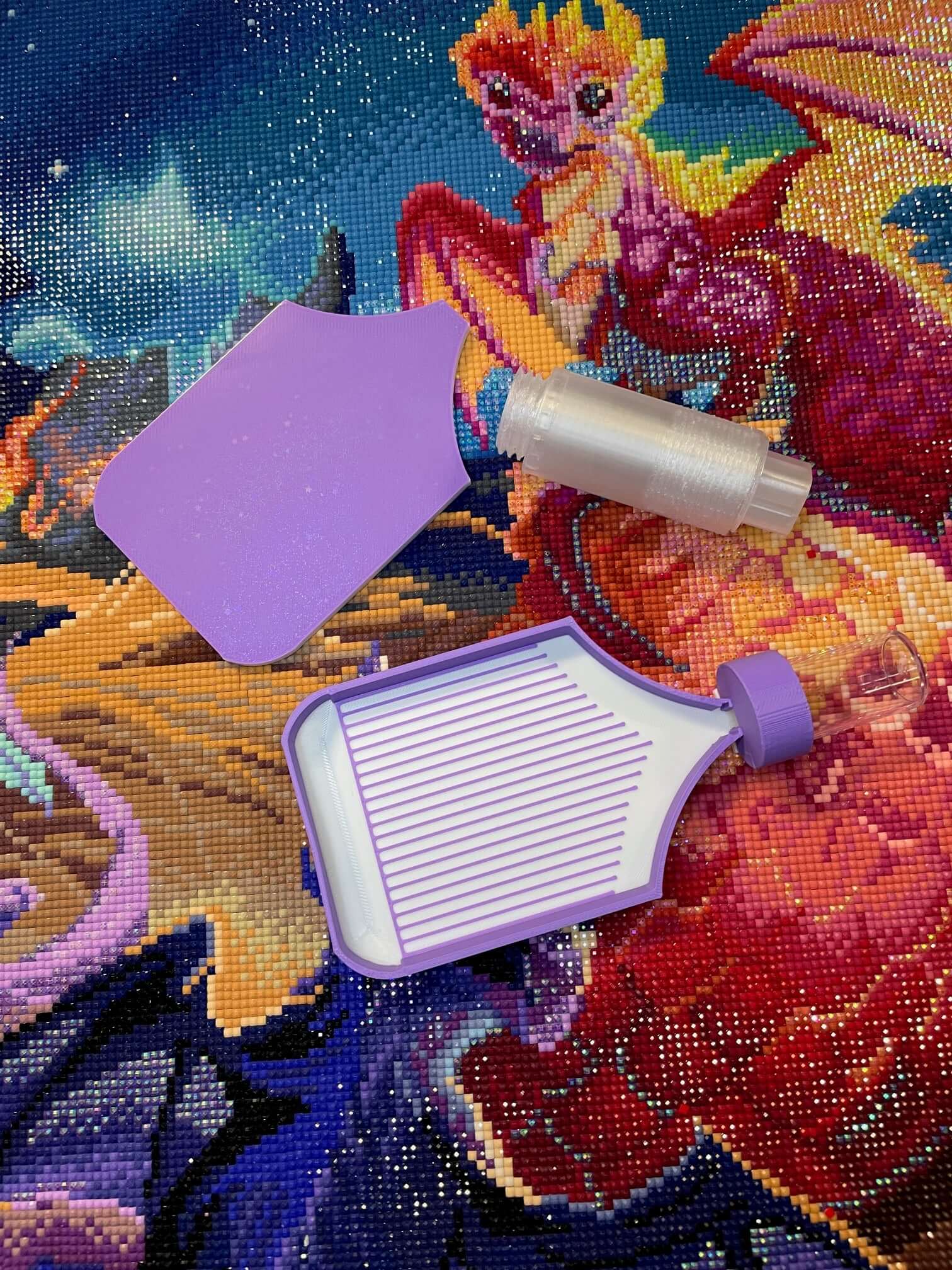 Purple and white Dragonling Screw & Shake diamond art tray on a colorful dragon-themed canvas background.