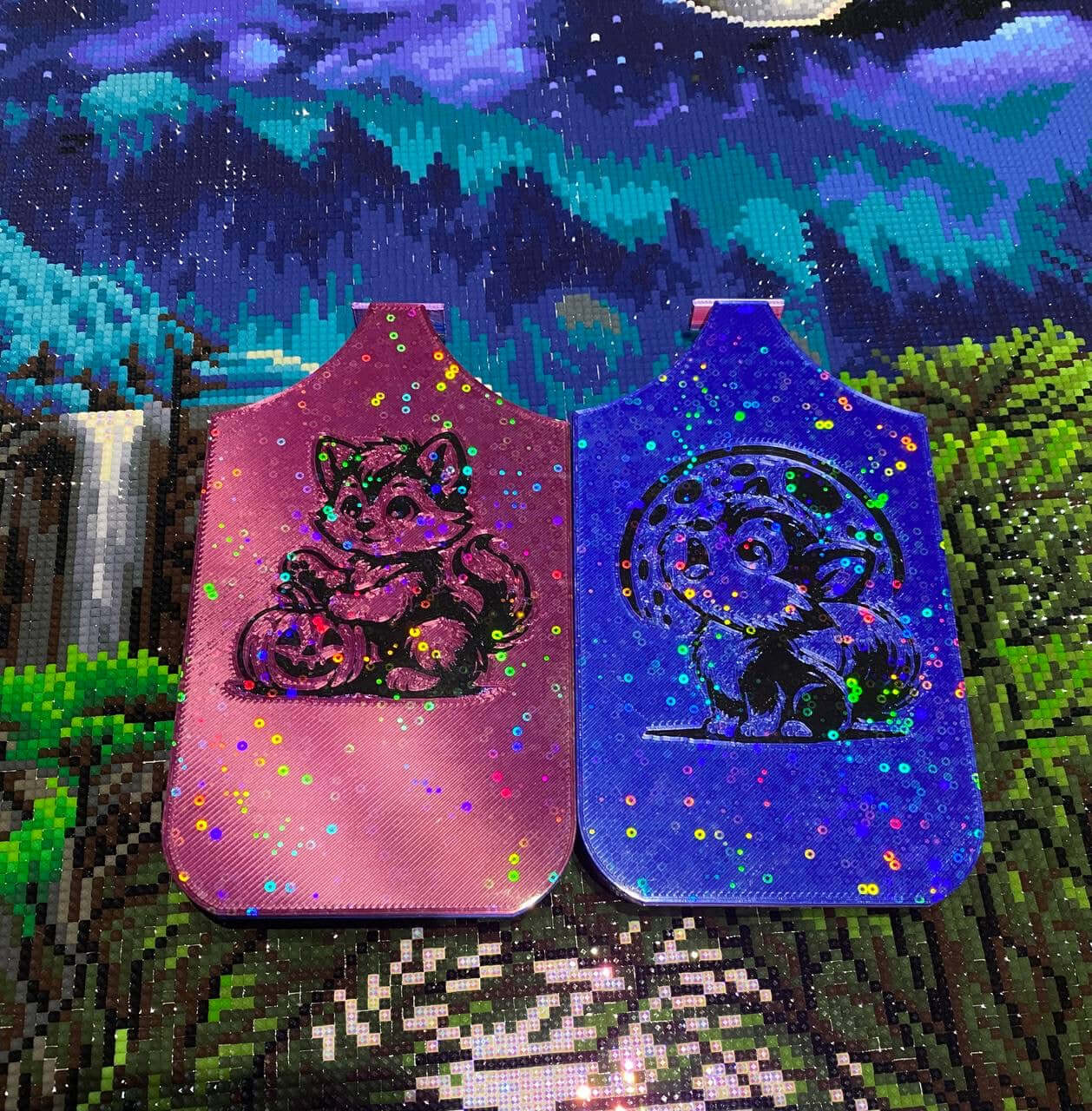 Two colorful dragon Diamond Art trays with Halloween-themed designs featuring a werewolf pup and pumpkin, set against a scenic background.