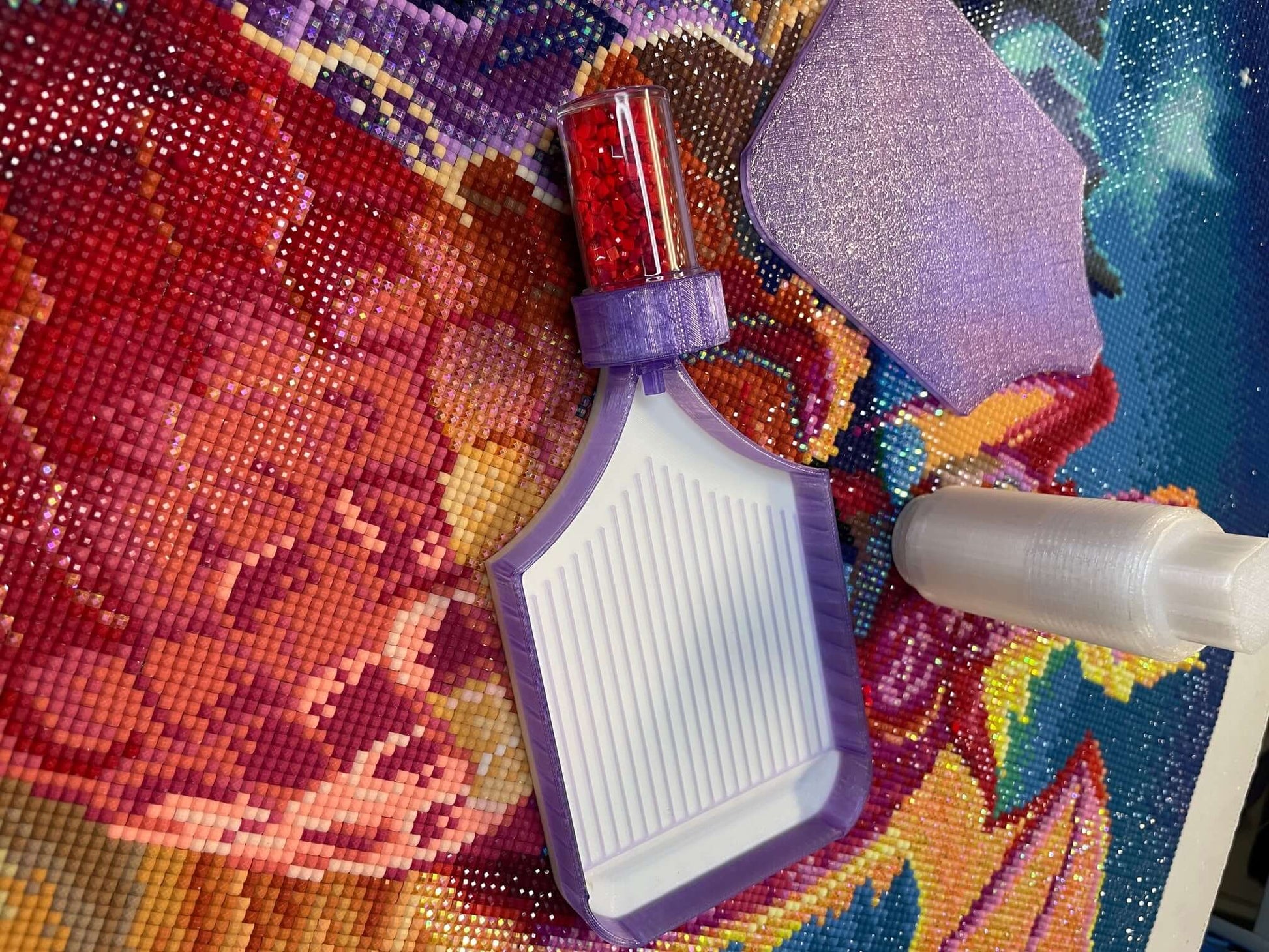 Dragonling Screw & Shake Tray with white base and purple edge shown on colorful diamond painting canvas.